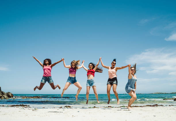 istock Happy female friends jumping at beach 876000436