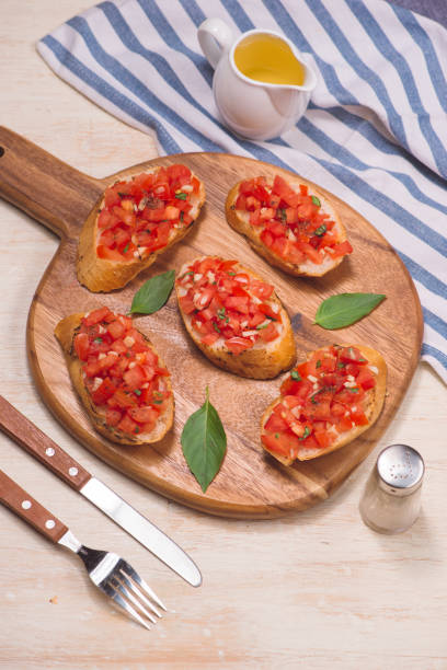 istock Italian bruschetta with roasted tomatoes, mozzarella cheese and herbs on a cutting board 876003942