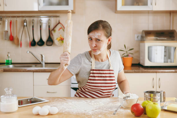 istock A young perplexed and confused woman sitting at a table with rolling pin and flour and going to prepare a Christmas cakes in the kitchen. Cooking home. Prepare food. 876004760