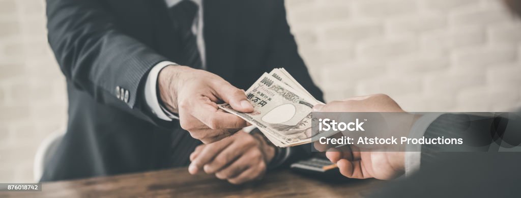 Businessman accepting Japanese Yen money Businessman accepting Japanese Yen money as a bribe, loan or payment in the office - panoramic banner Debt Stock Photo