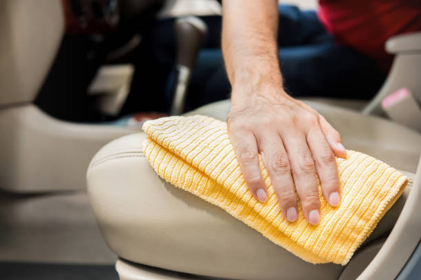 A man cleanining beige leather car seat with microfiber cloth A man cleanining beige leather car seat with microfiber cloth - auto detailing and valeting concept leather care stock pictures, royalty-free photos & images