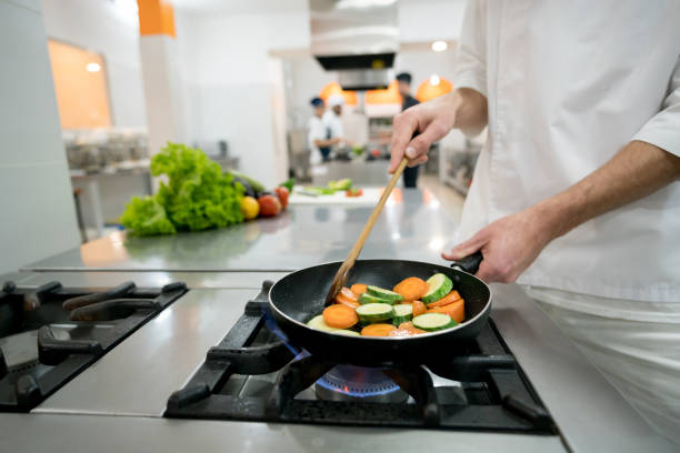 istock Unrecognizable male chef cooking vegetables on a frying pan 876026894