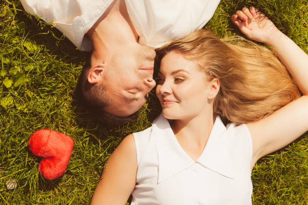 istock Man and woman lying on grass having date 876029592