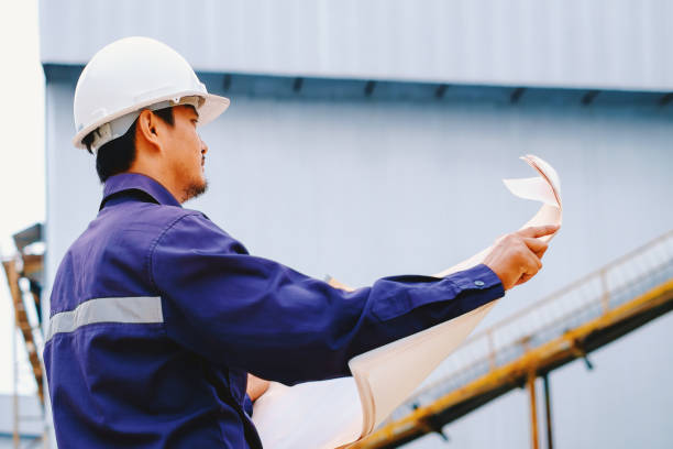 istock Engineer with white safety helmet holding project plan at construction outdoor site background, industrial concept 876034502