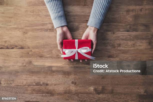 Frau Hände Im Grauen Pullover Auf Holztisch Geben Rote Weihnachtsgeschenkbox Stockfoto und mehr Bilder von Geschenk
