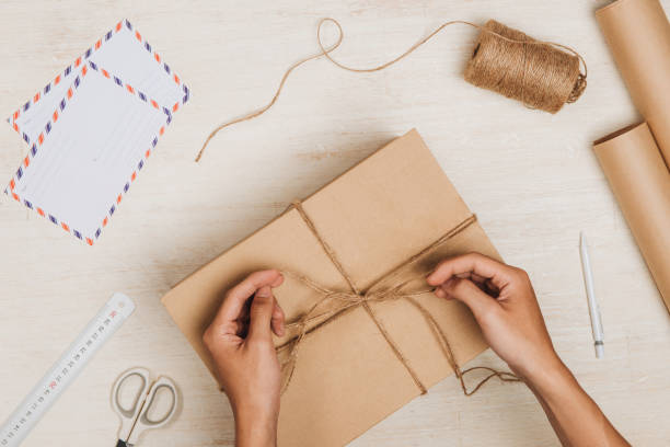 istock Man wrapping gift. A parcel wrapped in brown paper and tied with rough twine 876042014