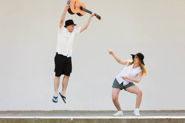 istock Man jumping with guitar, woman pointing at him 876056776