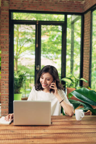 istock Confident smiling asian woman using phone and laptop 876059248