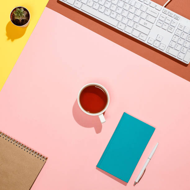 istock Modern colorful freelancer's workspace. Flat lay composition of keyboard, cactus, diary with pen and cup of tea on colorful desk. Pink, yellow, aquamarine and and brown colours 876095880