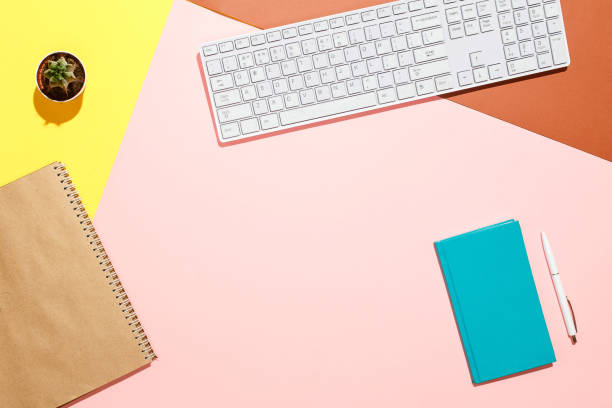 istock Modern positive workspace. Flat lay composition of keyboard, cactus, diary with pen on colorful desk. Pink, yellow, aquamarine and and brown colours 876097396