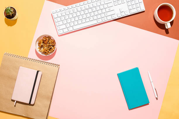 istock Modern feminine home workspace. Flat lay composition of keyboard, cactus, diary with pen and cup of tea on colorful desk. Pink, yellow, aquamarine and and brown colours. Blogger's home office 876099118