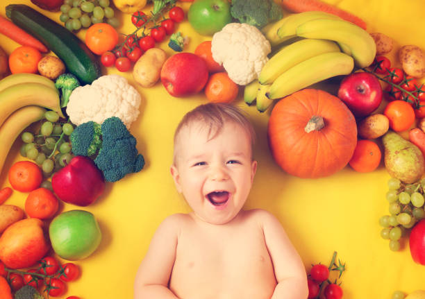 ребенок в окружении фруктов и овощей - baby carrot snack healthy eating small стоковые фото и изображения