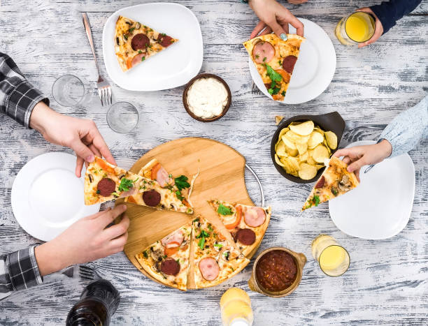 people eating pizza with chips and sauces