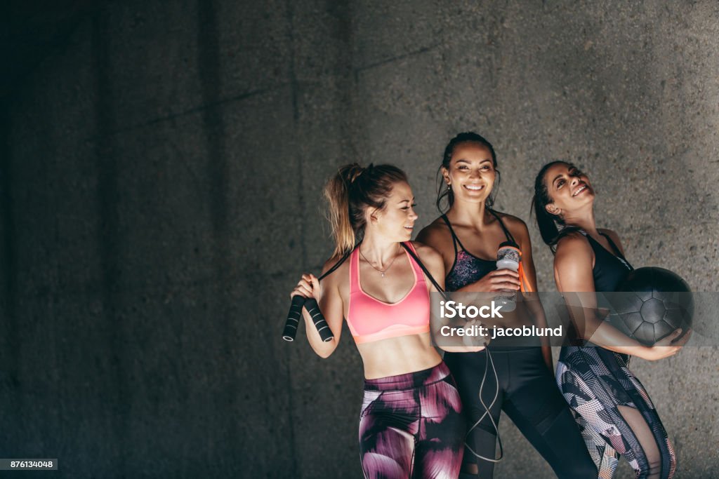 Group of female friends relaxing after workout Happy young women standing together and smiling after exercising. Group of female friends relaxing after workout outdoors. Exercising Stock Photo