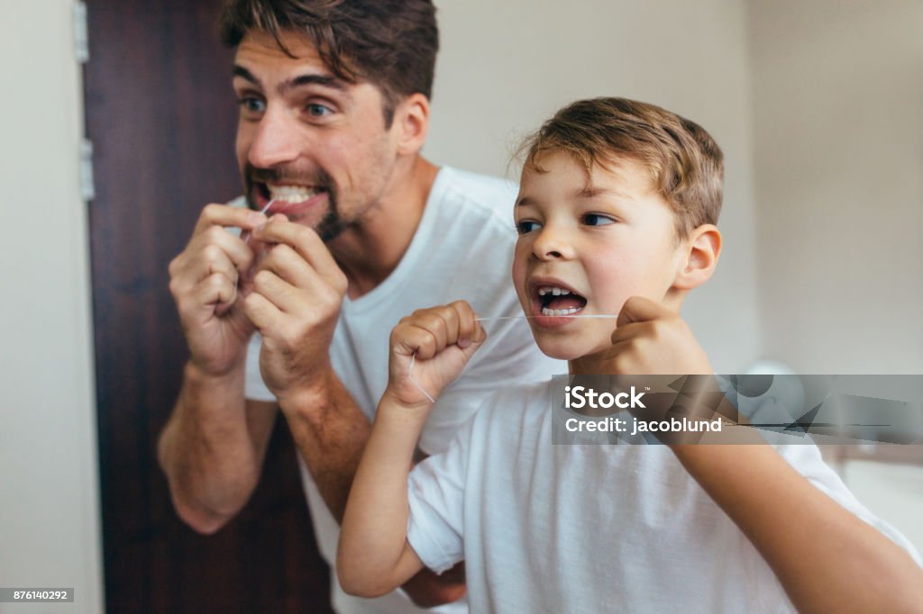 Père et fils, nettoyer les dents avec la soie dentaire - Photo de Fil dentaire libre de droits