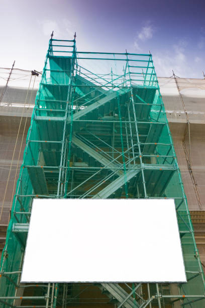 istock Metal scaffolding, with prefabricated components and blank billboard, to work on the facade for the renovation of the plaster wall 876144146