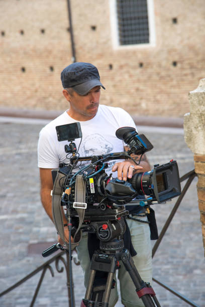 Front view. Video camera operator (cameraman) filming movie scene on outdoor location. Detail of professional camera equipment Front view. Video camera operator (cameraman) filming movie scene on outdoor location. Detail of professional camera equipment. Italy, Urbino movie sound clips stock pictures, royalty-free photos & images