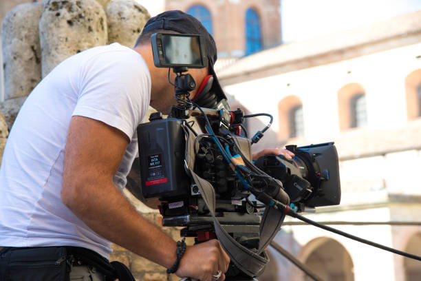 Behind the scene. Video camera operator (cameraman) filming movie scene on outdoor location. Detail of professional camera equipment Behind the scene. Video camera operator (cameraman) filming movie scene on outdoor location. Detail of professional camera equipment. Italy, Urbino movie sound clips stock pictures, royalty-free photos & images