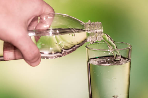 istock water is poured into a glass on green  soft focus background 876187690
