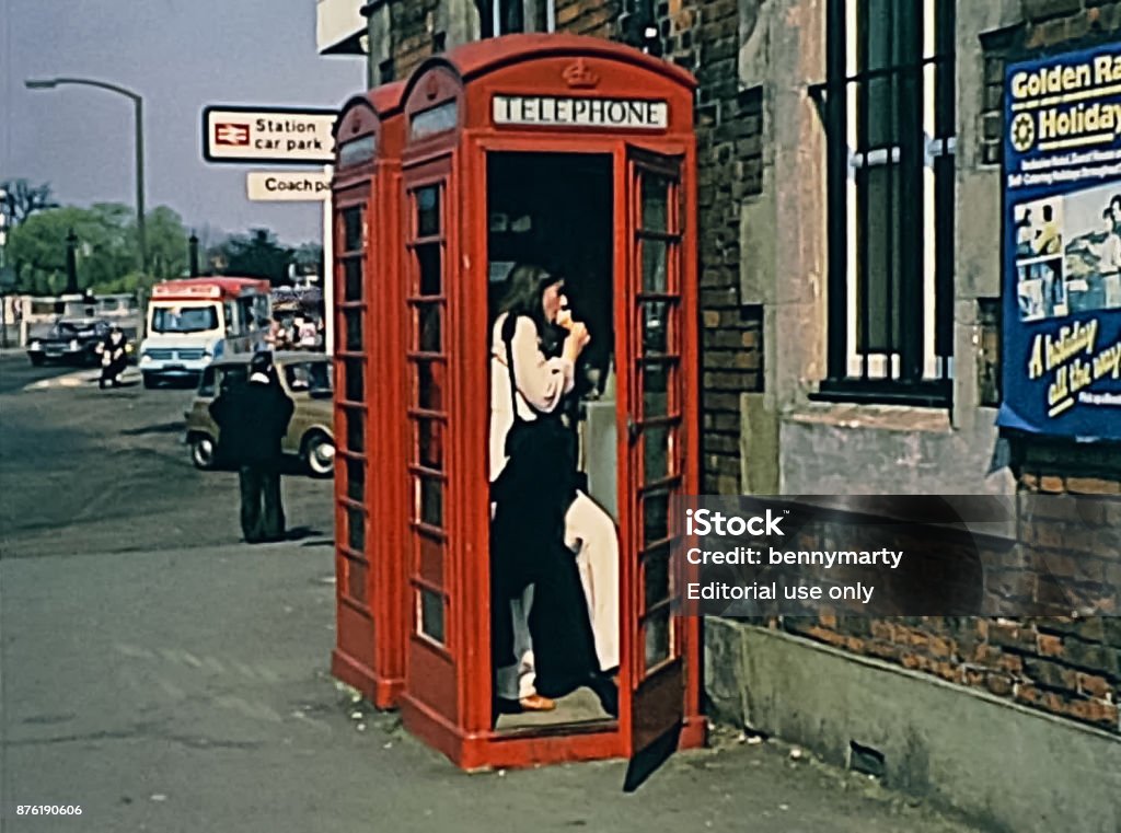 Red telephone box LONDON, UNITED KINGDOM - CIRCA 1979: Red telephone box with woman in vintage clothing in Oxford street. Historic 1970s image 1970-1979 Stock Photo