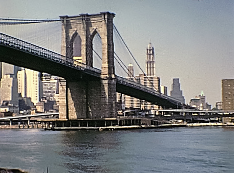 New York, United States of America - circa 1970: ancient Manhattan skyline on seventy, vintage Brooklyn Bridge and Empire State Building, from boat tour Circle Line Sightseeing Cruise on East river.
