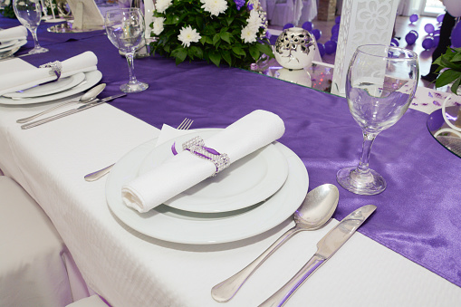 A table set up for the bride and groom at a wedding celebration, with placards, flowers and crockery