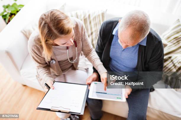 Foto de Visitante De Saúde E Um Homem Sênior Com Tablet Durante Visita Em Casa e mais fotos de stock de Paciente