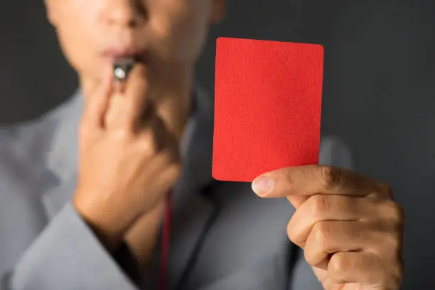 Businesswoman blowing a whistle and showing red card.