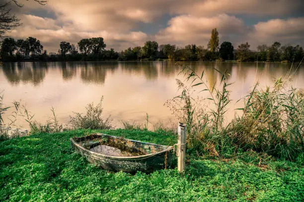 Autumn sunset on a waterway of the Dordogne river near Bordeaux in France with a boat on the grass.