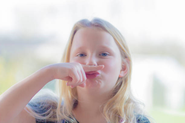 pre-teen rebel blonde making a finger moustache - costume mustache child disguise imagens e fotografias de stock