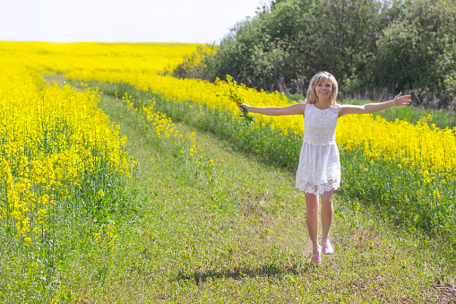 Girl with bouquet of rape flowers walking on country road