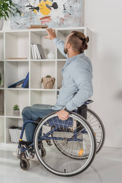 istock man on wheelchair trying to reach for book 876303628