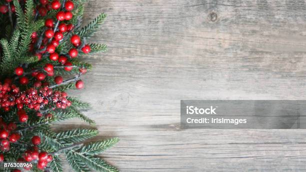 Holiday Evergreen Branches And Berries Over Wood Stock Photo - Download Image Now - Christmas, Backgrounds, Holiday - Event