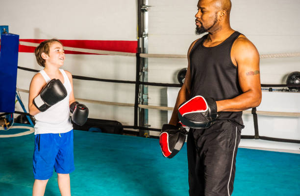 istock Boxing coach with a young athlete in a boxing gym. 876312094