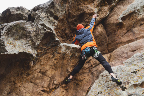 hipster - scalatore all'età di arrampicarsi su una bellissima roccia senza assicurazione e casco - arch top foto e immagini stock