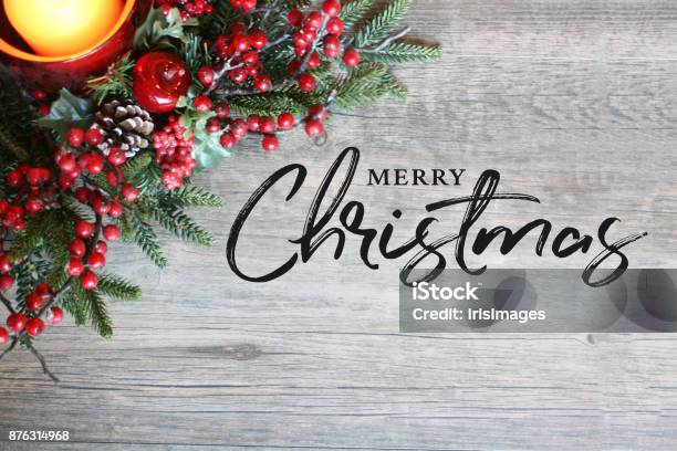 Merry Christmas Text Candle Pine Tree Branches And Berries In Top Corner Over Rustic Wood Stock Photo - Download Image Now