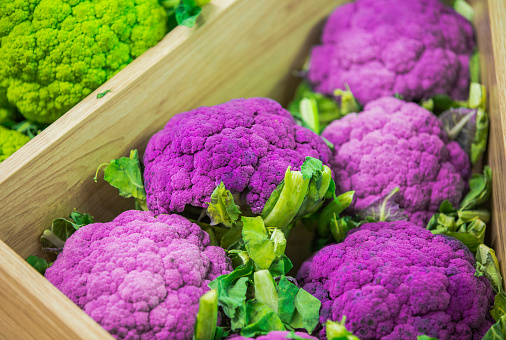 Fresh colorful vegetables on the counter of the store: purple cauliflower, Brussels sprouts.