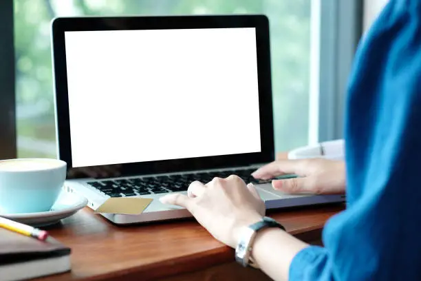 Photo of Woman hands typing laptop computer with blank screen for mock up while sitting in the cafe, technology and lifestyle concept