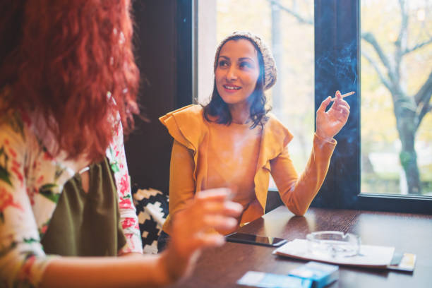 두 젊은 여성 흡연과 카페에 있는 재미 - holding cigarette 뉴스 사진 이미지