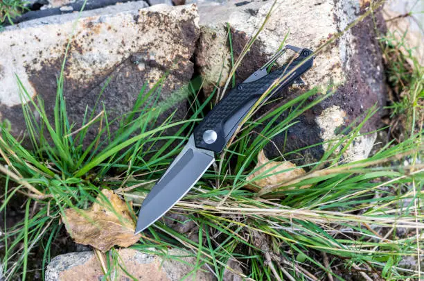 Photo of Pocket knife. Knife with a carbine. Photo knife in nature.