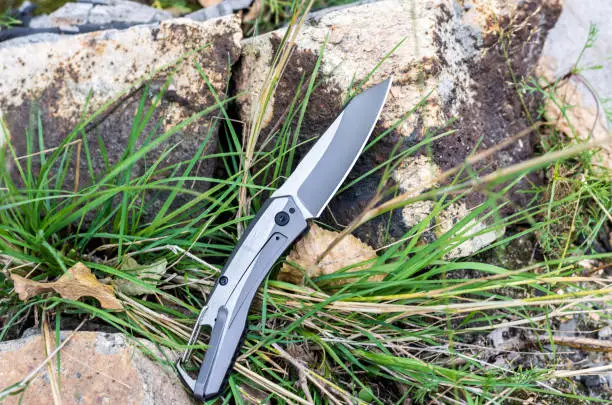 Photo of Pocket knife with a carbine. Photo knife in nature. Horizontal frame.