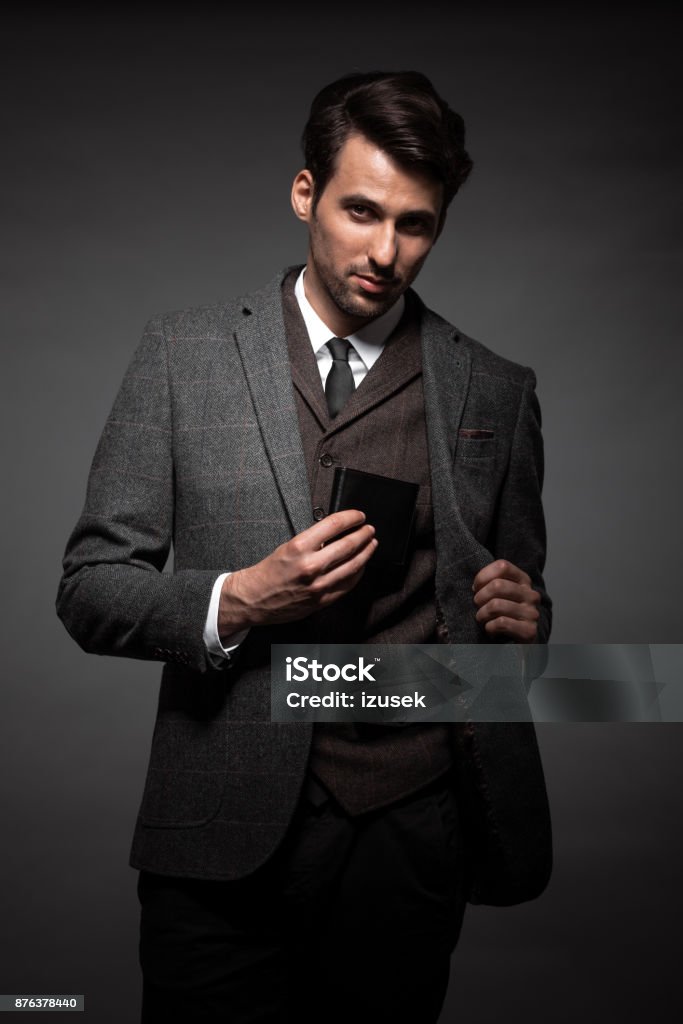Businessman keeping wallet in the jacket Portrait of young businessman keeping his wallet in the jacket on black background. Wallet Stock Photo