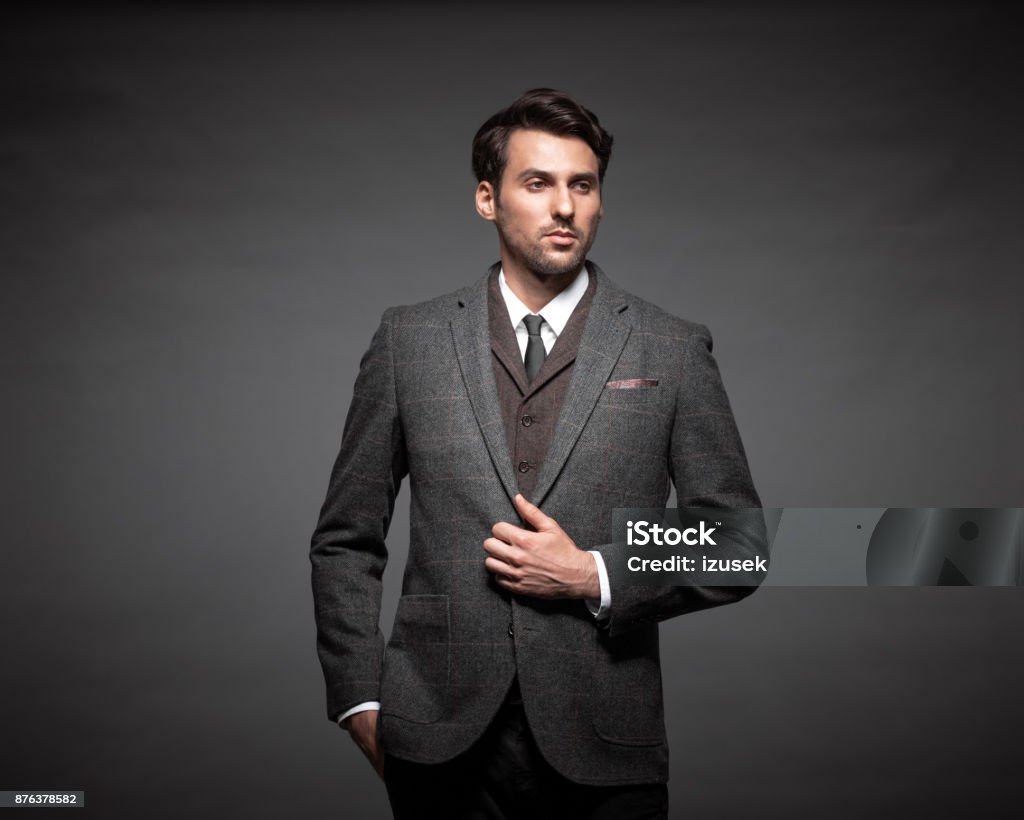 Handsome young businessman in suit Portrait of handsome young businessman in suit standing against black background and looking away. Fashionable Stock Photo