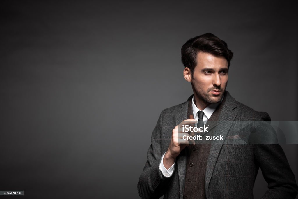 Handsome man in suit smoking cigar Portrait of young man in suit smoking cigar and looking away on black background 30-34 Years Stock Photo