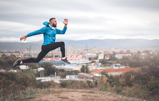 Photography of a 28 years old man outdoors. He is doing stretching exercise to warm up his body