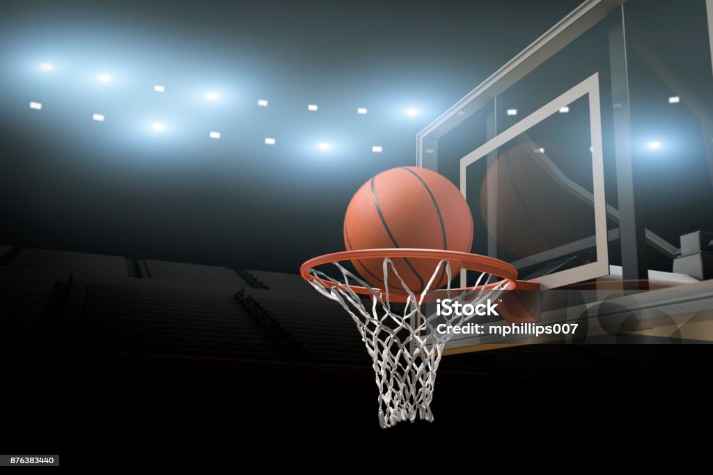 Basketball Stadium Arena Background A basketball going through a basketball goal mid air in  professional basketball stadium or arena with stadium lights and flares and copy space for text. Basketball - Sport Stock Photo