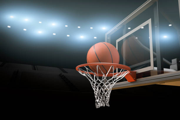 Basketball Stadium Arena Background A basketball going through a basketball goal mid air in  professional basketball stadium or arena with stadium lights and flares and copy space for text. college basketball court stock pictures, royalty-free photos & images