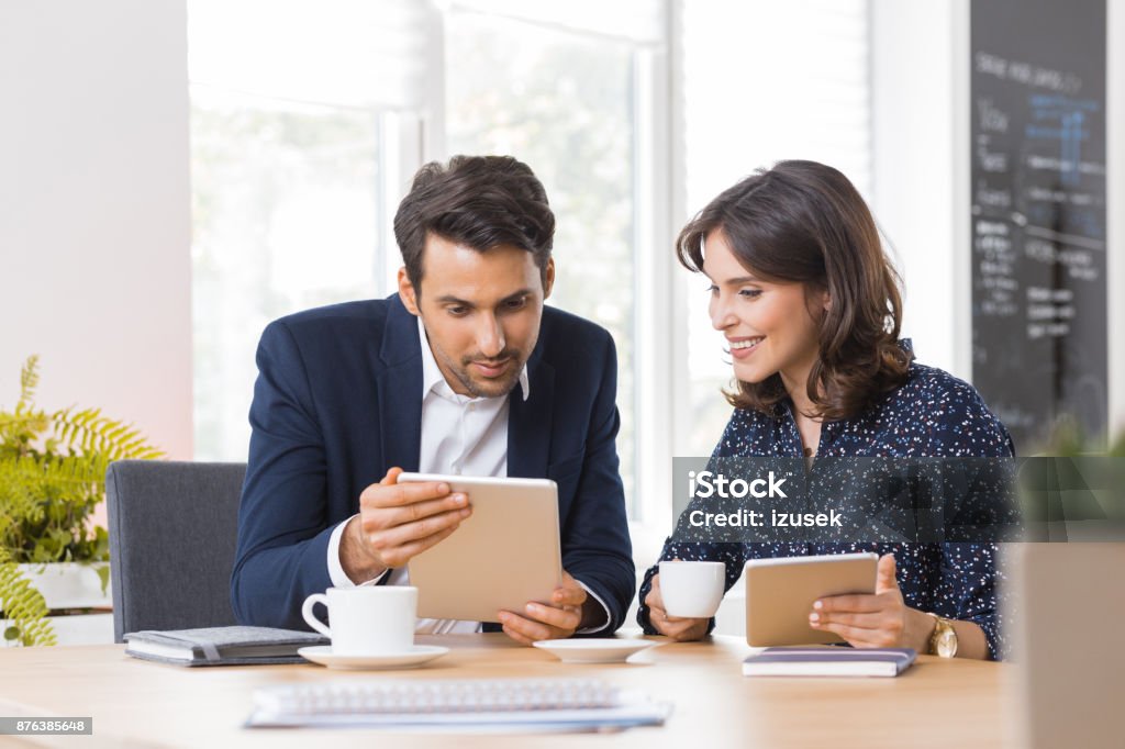 Business couple having lunch meeting Two business colleagues sitting in a cafe and using digital tablet. Business couple having lunch meeting in a cafe. Business Stock Photo