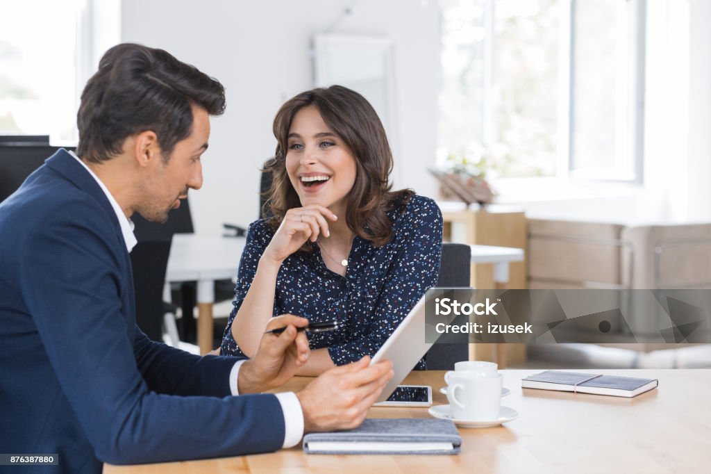 Business partners having lunch meeting Two business partners sitting in a cafe with digital tablet. Happy business couple having lunch meeting in a cafe. Adult Stock Photo