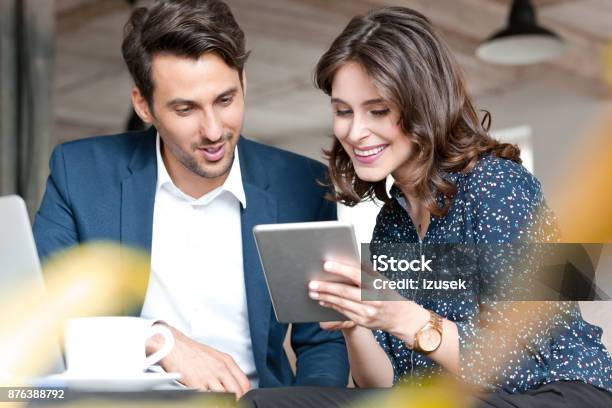 Couple Of Young Business People Looking At Digital Tablet Stock Photo - Download Image Now